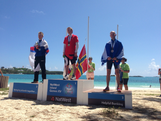 Bobby Oag who won a gold medal for Orkney in yesterday's Island Games triathlon stands at the top of the podium as the Orkney flag gets lifted behind him.