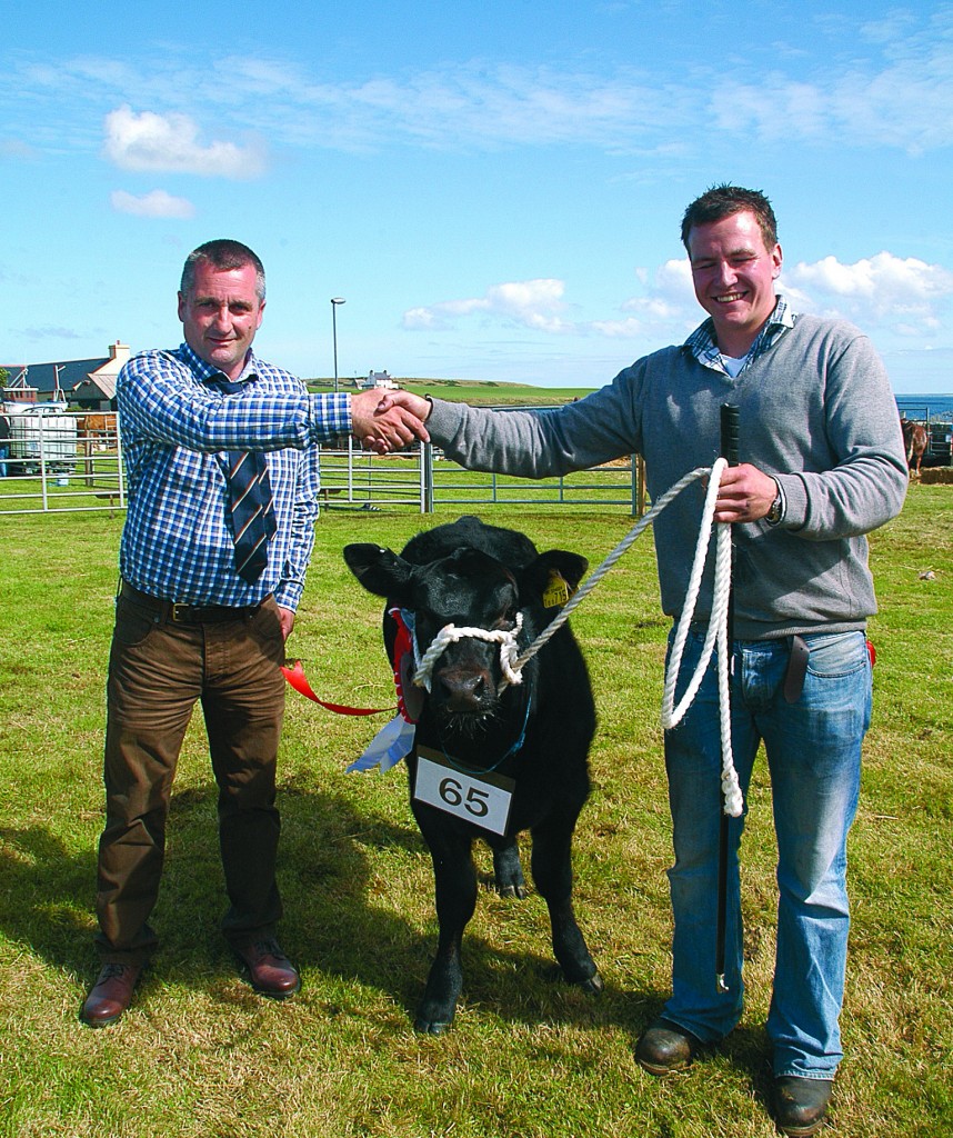 Cattle judge, Gary Flett congratulates Frazer Leslie who brought out the overall cattle champion.