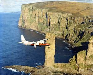 A Loganair Islander passes the Old Man of Hoy.