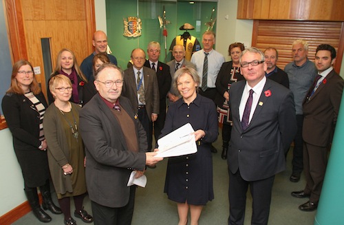 Kirkwall BID chairwoman Karen Scholes hands the petition to OIC vice-convener, Councillor Jim Foubister, as OIC elected members and officials watch on alongside town centre business owners. (www.theorcadianphotos.co.uk)